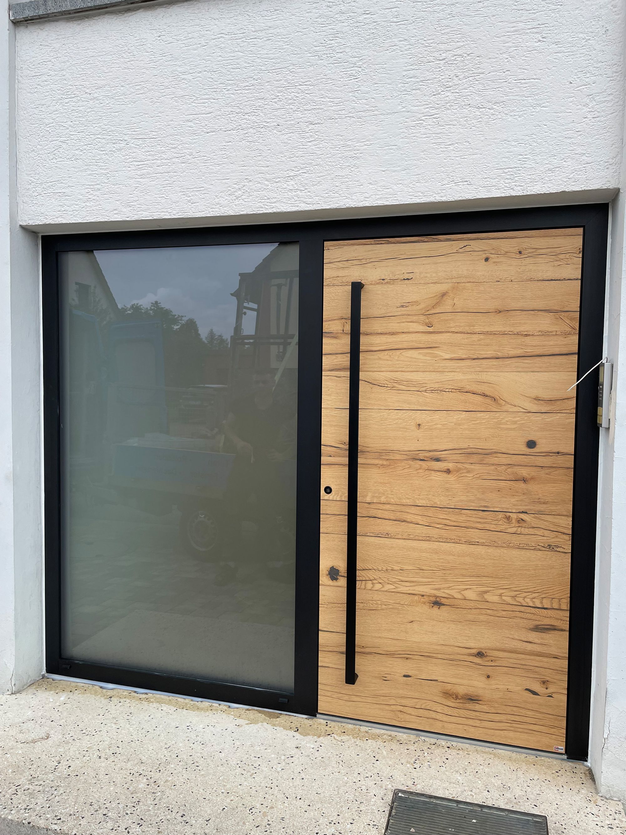 Eine Eingangstür mit einer Glasfront links und rechts eine Tür aus Echtholz.